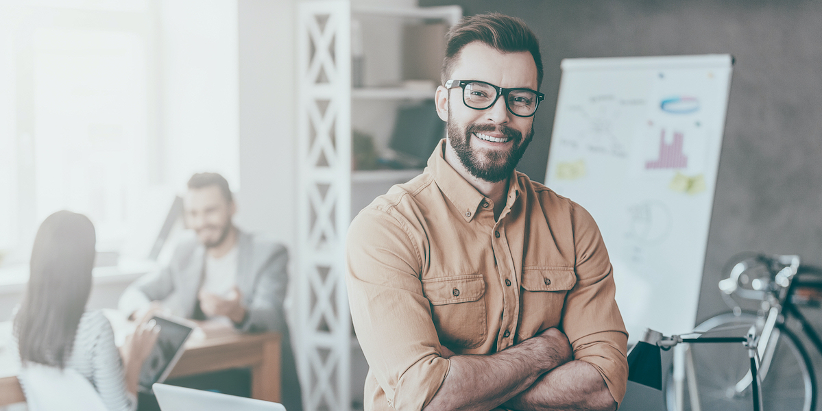 Business owner, employees behind him, smiles thanks to ghostwriting driving his business